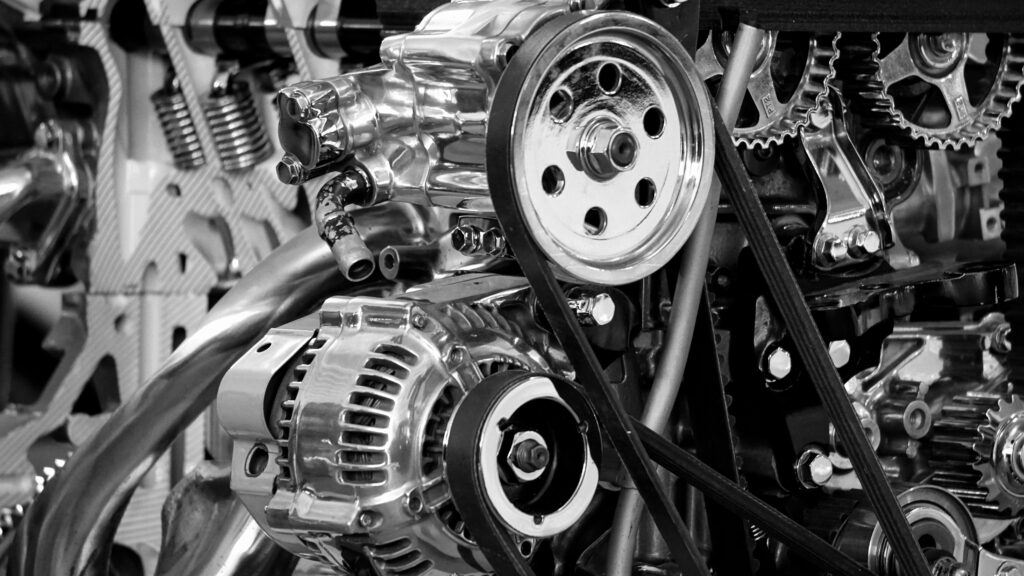 Ghid util pentru motorul 1.9 diesel Close-up of a shiny car engine showing polished metal parts and gears in black and white.